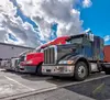 Semi trucks lined up outside a warehouse.