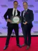 Two men holding the 2025 APEX award plaque